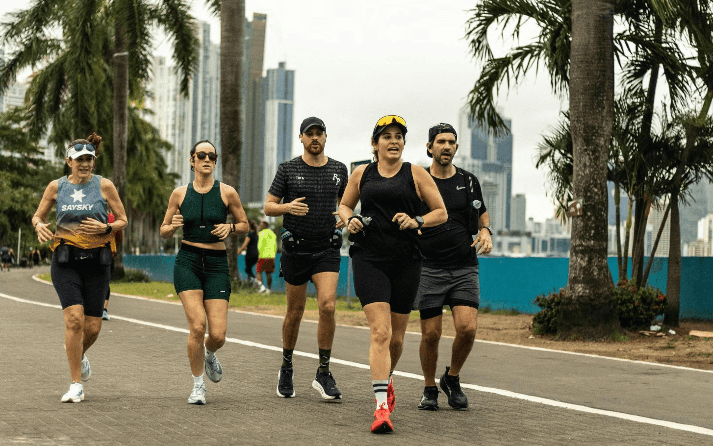 A group of runners training together on a palm-lined waterfront path